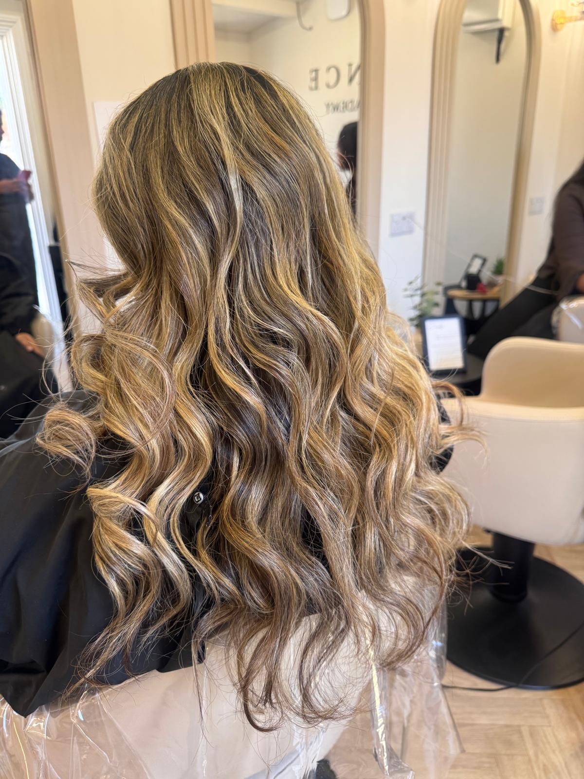 Long blonde balayage styled in loose curls